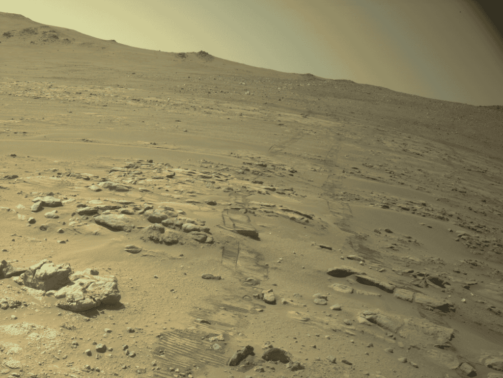 Imagem da superfície de Marte mostra terreno rochoso e marcas deixadas pelas rodas do rover Perseverance durante sua exploração.