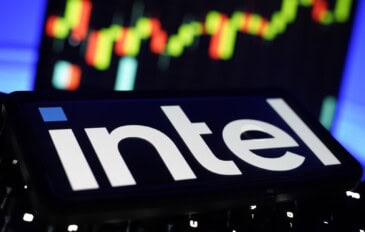 Logotipo da Intel exibido em uma tela, com um gráfico de cotações da bolsa de valores desfocado ao fundo