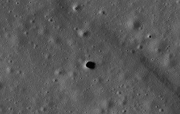 Superfície da Lua com diversas crateras e uma abertura escura no centro, identificada como Marius Hills Pit.