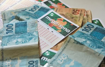cartela da mega-sena entre notas de reais