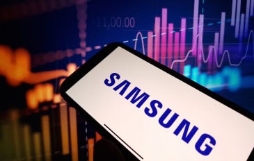 Logo da Samsung em um smartphone; ao fundo, gráficos financeiros