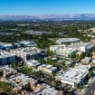 Vista aérea do Vale do Silício, na Califórnia, com edifícios comerciais, áreas residenciais, vegetação e o Apple Park ao fundo