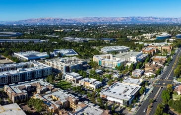 Vista aérea do Vale do Silício, na Califórnia, com edifícios comerciais, áreas residenciais, vegetação e o Apple Park ao fundo